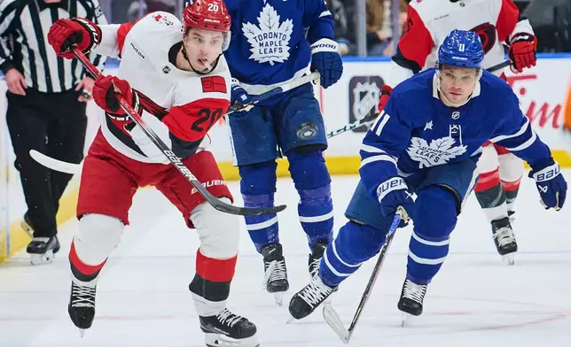 Carolina Hurricanes' Sebastian Aho (20) and Toronto Maple Leafs' Max Domi (11) battle for the puck during first-period NHL hockey game action in Toronto, Friday, March 20, 2026. (Sammy Kogan/The Canadian Press via AP)