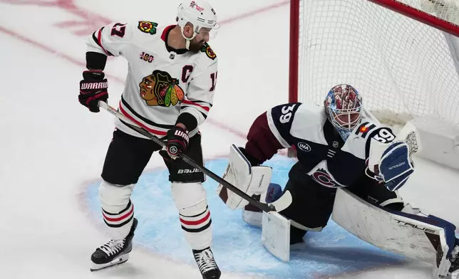 Chicago Blackhawks left wing Nick Foligno, left, redircts a shot into the glove of Colorado Avalanche goaltender MacKenzie Blackwood in the third period of an NHL hockey game Saturday, Feb. 28, 2026, in Denver. (AP Photo/David Zalubowski)