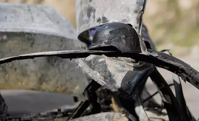 A burned press helmet rests on the charred car that was carrying Hezbollah's al-Manar TV correspondent Ali Shoeib, Beirut's based Al-Mayadeen TV reporter Fatima Ftouni and her brother, video journalist Mohammed Ftouni, before they were killed in an Israeli airstrike, in the town of Jezzine, south Lebanon, Saturday, March 28, 2026. (AP Photo/Mohammed Zaatari)