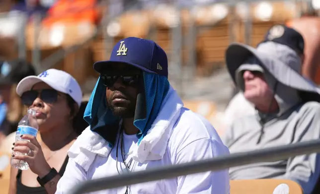 Baseball fans watch the Los Angeles Dodgers play the San Francisco Giants during the fifth inning of a spring training baseball game with the heat forcing the game to end early, Wednesday, March 18, 2026, in Phoenix. (AP Photo/Ross D. Franklin)