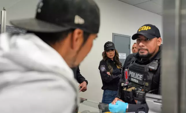 FILE - Homeland Security Secretary Kristi Noem, center, watches as officers speak with a person passing through the San Ysidro Port of Entry, March 16, 2025, in San Diego. (AP Photo/Alex Brandon, File)
