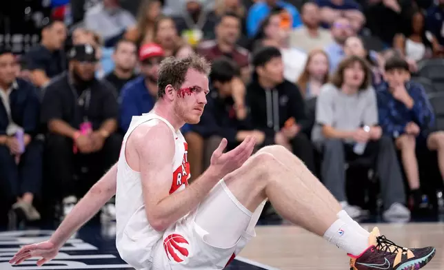 Toronto Raptors center Jakob Poeltl sits on the floor after being inured on a play during the first half of an NBA basketball game against the Los Angeles Clippers, Wednesday, March 25, 2026, in Inglewood, Calif. (AP Photo/Mark J. Terrill)