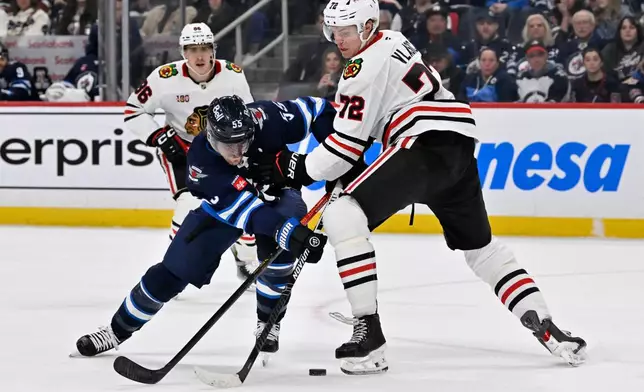 Chicago Blackhawks' Alex Vlasic (72) checks Winnipeg Jets' Mark Scheifele (55) during the second period of their NHL hockey game in Winnipeg, Tuesday March 3, 2026. (Fred Greenslade/The Canadian Press via AP)
