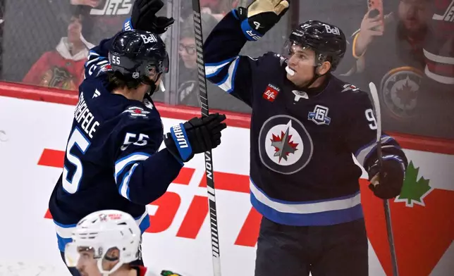 Winnipeg Jets' Mark Scheifele (55) celebrates his game-winning goal against the Chicago Blackhawks with Cole Perfetti (91) during the overtime period of their NHL hockey game in Winnipeg, Tuesday March 3, 2026. (Fred Greenslade/The Canadian Press via AP)