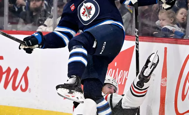 Winnipeg Jets' Cole Koepke (top) collides with Chicago Blackhawks' Sam Rinzel (6) during the second period of their NHL hockey game in Winnipeg, Tuesday March 3, 2026. (Fred Greenslade/The Canadian Press via AP)