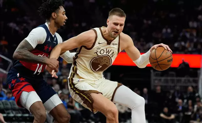 Golden State Warriors center Kristaps Porzingis (7) moves the ball while defended by Washington Wizards forward Leaky Black (14) during the second half of an NBA basketball game, Friday, March 27, 2026, in San Francisco. (AP Photo/Godofredo A. Vásquez)