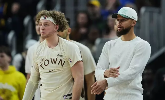 Golden State Warriors' Stephen Curry, right, gestures from the bench during the first half of an NBA basketball game against the Washington Wizards, Friday, March 27, 2026, in San Francisco. (AP Photo/Godofredo A. Vásquez)
