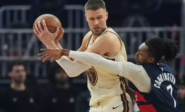 Golden State Warriors center Kristaps Porzingis, left, looks for an open teammate whiel defended by Washington Wizards guard Bub Carrington during the first half of an NBA basketball game, Friday, March 27, 2026, in San Francisco. (AP Photo/Godofredo A. Vásquez)