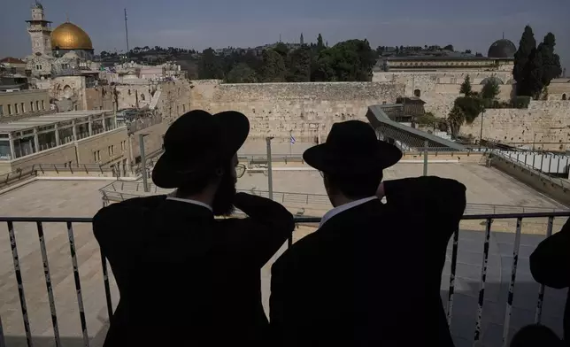 Ultra-Orthodox Jewish men stand near an empty Western Wall at Jerusalem's Old City, Thursday, March 19, 2026, as the area remains closed to visitors under nationwide Home Front Command restrictions banning large gatherings amid the war with Iran. (AP Photo/Mahmoud Illean)