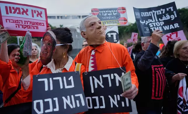 People dressed in orange prison jumpsuits and wearing masks of Israel's Prime Minister Benjamin Netanyahu and National Security Minister Itamar Ben Gvir gather to demonstrate against the ongoing war with Iran, in Tel Aviv, Israel, Thursday, March 19, 2026. Boards read in Hebrew: "Iran is an asset" and "Terror is an asset. (AP Photo/Maya Levin)
