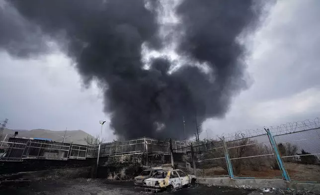 A thick plume of smoke rises from an oil storage facility hit by a U.S.-Israeli strike late Saturday in Tehran, Iran, Sunday, March 8, 2026. (AP Photo/Vahid Salemi)
