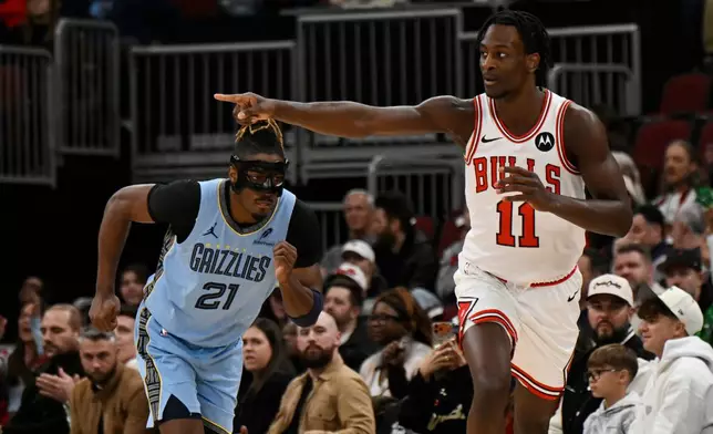 Chicago Bulls' Leonard Miller (11) celebrates after making a 3-point basket while Memphis Grizzlies' Jahmai Mashack (21) looks on during the first half of an NBA basketball game in Chicago, Monday, March 16, 2026. (AP Photo/Paul Beaty)