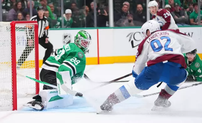 Dallas Stars goaltender Jake Oettinger, left, blocks a shot as Colorado Avalanche left wing Gabriel Landeskog (92) attacks during the second period of an NHL hockey game Friday, March 6, 2026, in Dallas. (AP Photo/Julio Cortez)