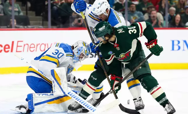St. Louis Blues goaltender Joel Hofer (30) protects the net while Blues defenseman Cam Fowler (17) and Minnesota Wild right wing Ryan Hartman (38) battle during the first period of an NHL hockey game Sunday, March 1, 2026, in St. Paul, Minn. (AP Photo/Ellen Schmidt)