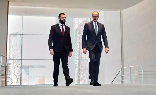 German Chancellor Friedrich Merz, right, and Syrian President Ahmad al-Sharaa arrive for a press conference in Berlin, Germany, Monday, March 30, 2026. (AP Photo/Markus Schreiber)