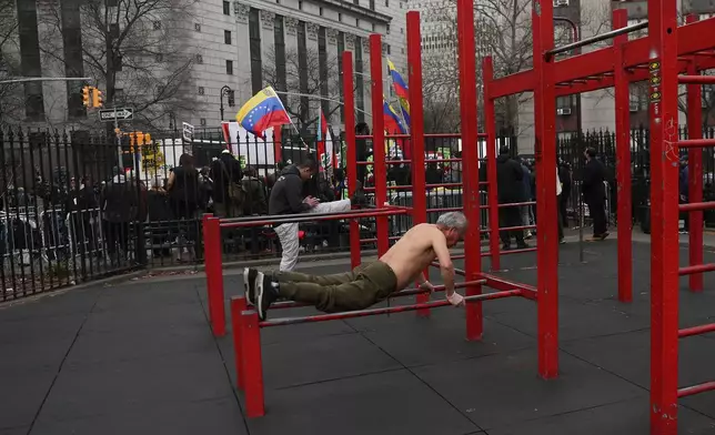 Men work out in Columbus Park as people protest outside Manhattan federal court before a pre-trial hearing in former Venezuela President Nicolas Maduro's drug trafficking case, Thursday, March 26, 2026, in New York. (AP Photo/Heather Khalifa)