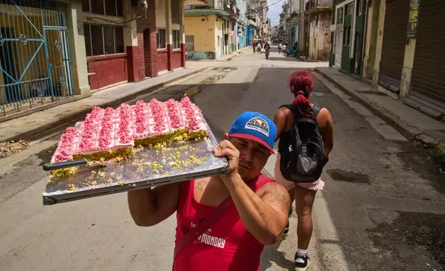 A street vendor selling pastries walks down the middle of the street looking for customers in Havana, Cuba, Thursday, March 19, 2026. (AP Photo/Ramon Espinosa)
