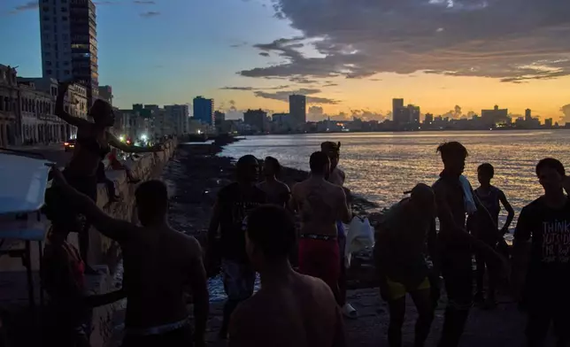 People watch the sunset from the Malecón during a blackout in Havana, Monday, March 16, 2026. (AP Photo/Ramon Espinosa)