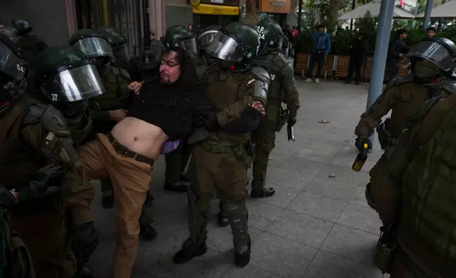 Riot police detain a protester during a march during World Water Day demanding greater environmental protection and animal welfare, in Santiago, Chile, Sunday, March 22, 2026. (AP Photo/Esteban Felix)