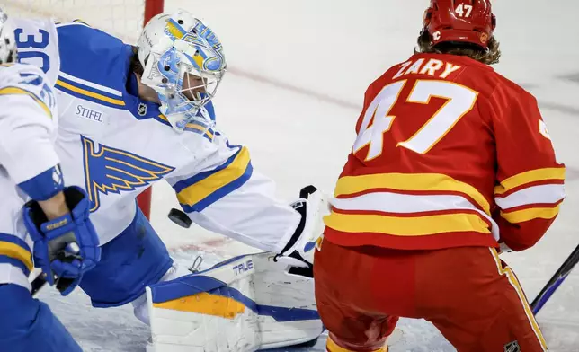 St. Louis Blues goalie Joel Hofer, left, lets in a goal from Calgary Flames' Connor Zary during the first period of an NHL hockey game in Calgary on Wednesday, March 18, 2026. (Jeff McIntosh/The Canadian Press via AP)