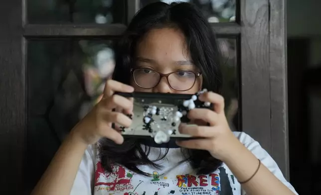 Maura Munthe plays Roblox on her mobile phone at her house in Jakarta, Indonesia, March 14, 2026. (AP Photo/Dita Alangkara)