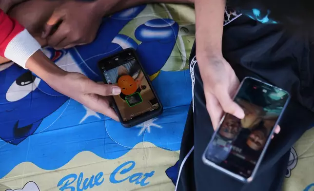 Teenage boys use their mobile phones to browse social media in Jakarta, Indonesia, March 16, 2026. (AP Photo/Dita Alangkara)