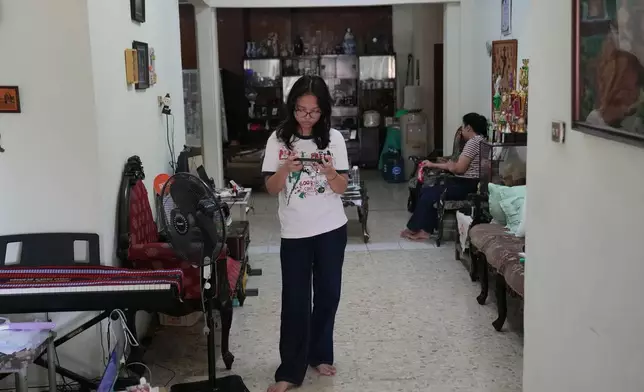 Maura Munthe plays Roblox on her mobile phone at her house in Jakarta, Indonesia, March 14, 2026. (AP Photo/Dita Alangkara)