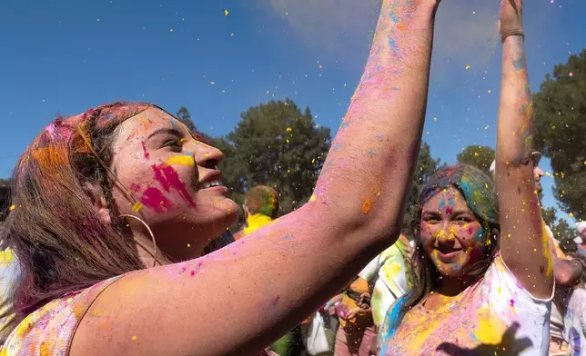 FILE- Devotees cheer and dance as colored powder is tossed onto them in celebration of Holi, the Hindu festival of colors, in Los Angeles, March 8, 2026. (AP Photo/Richard Vogel, File)