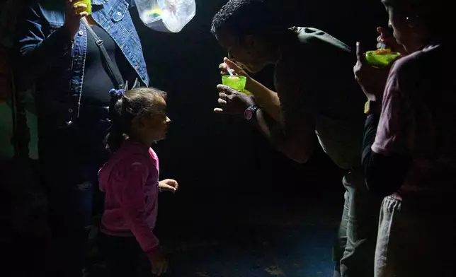 FILE- A man gives a girl a spoonful of soup on a street during a blackout in Havana, March 4, 2026. (AP Photo/Ramon Espinosa, File)