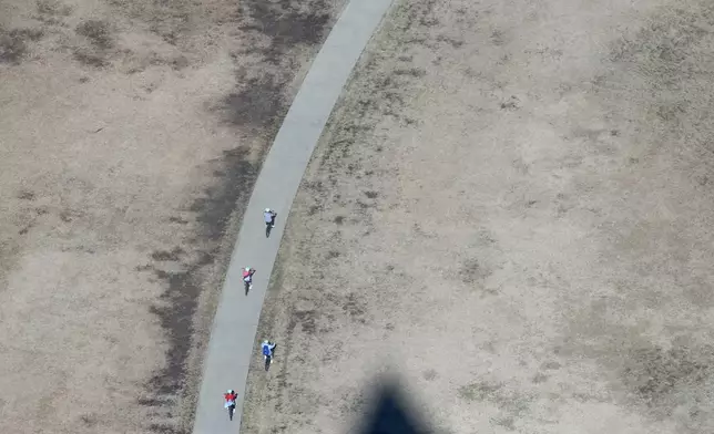 FILE- Bicyclists ride along the National Mall by a shadow of the Washington Monument, March 10, 2026, in Washington. (AP Photo/Jacquelyn Martin, File)