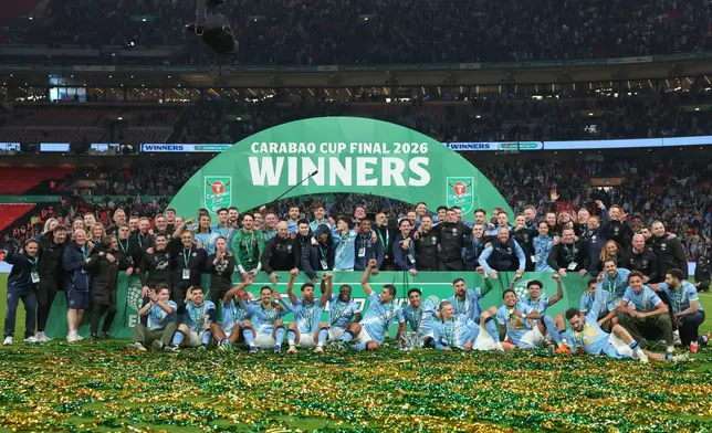 Manchester City players and staff celebrate with the trophy after winning the English League Cup final soccer match between Arsenal and Manchester City in London, Sunday, March 22, 2026. (AP Photo/Richard Pelham)
