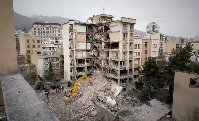 Iranian Red Crescent emergency workers use a bulldozer to clear rubble from a residential building that was hit in an earlier U.S.-Israeli strike in Tehran, Iran, Monday, March 23, 2026. (AP Photo/Vahid Salemi)