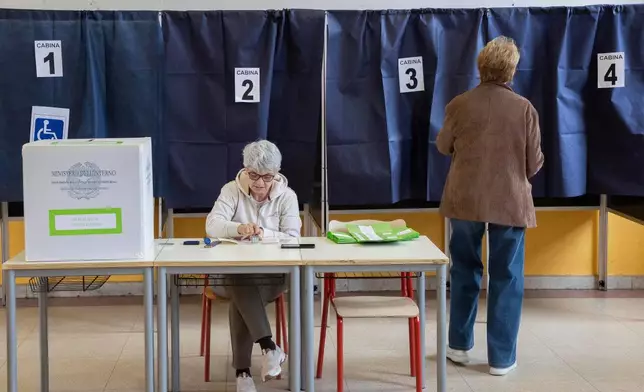 A woman arrives to vote in a referendum on judicial reform, at a polling station in Milan, Italy, Sunday March 22, 2026. (Marco Ottico/Lapresse via AP)