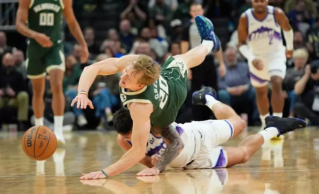 Milwaukee Bucks' AJ Green (20) and Utah Jazz's John Konchar, bottom, dive for the ball during the first half of an NBA basketball game Saturday, March 7, 2026, in Milwaukee. (AP Photo/Aaron Gash)