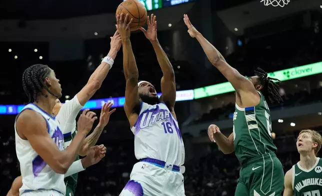 Utah Jazz's Elijah Harkless (16) looks to shoot between Milwaukee Bucks' Cam Thomas, second from right, and Ryan Rollins, back left, during the first half of an NBA basketball game Saturday, March 7, 2026, in Milwaukee. (AP Photo/Aaron Gash)