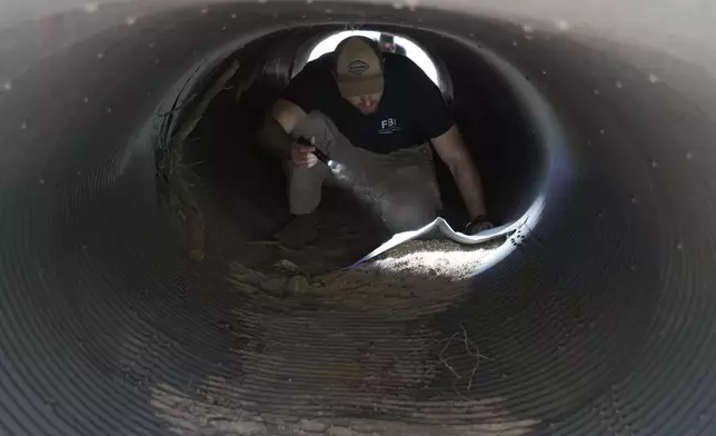 FILE - An investigator searches inside a culvert in the neighborhood where Annie Guthrie, whose mother Nancy Guthrie has been missing for more than a week, lives outside Tucson, Ariz., Feb. 10, 2026. (AP Photo/Ty ONeil, File)