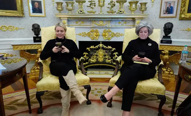 FILE - White House press secretary Karoline Leavitt and White House chief of staff Susie Wiles check their phones as President Donald Trump speaks in the Oval Office of the White House in Washington, Feb. 2, 2026. (AP Photo/Alex Brandon, File)