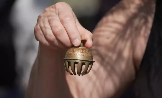 Forest therapy guide Shawn Ramsey rings a tiny brass bell during a "forest bathing" session at the J.C. Raulston Arboretum in Raleigh, N.C., on Sunday, March 22, 2026. (AP Photo/Allen G. Breed)