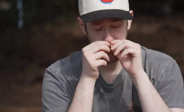 Alan Mintz smells a crushed conifer twig during a "forest bathing" session at the J.C. Raulston Arboretum in Raleigh, N.C., on Sunday, March 22, 2026. (AP Photo/Allen G. Breed)