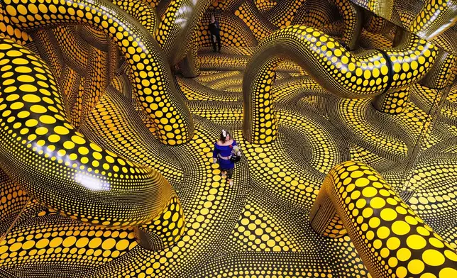 People walk through the artwork 'Infinity Mirrored Room' during a preview of the new major exhibition of legendary Japanese artist Yayoi Kusama at the Museum Ludwig in Cologne, Thursday, March 12, 2026. (AP Photo/Martin Meissner)
