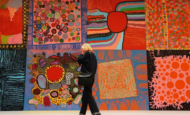 A woman views the artwork 'My Eternal Soul Series' during a preview of the new major exhibition of legendary Japanese artist Yayoi Kusama at the Museum Ludwig in Cologne, Thursday, March 12, 2026. (AP Photo/Martin Meissner)