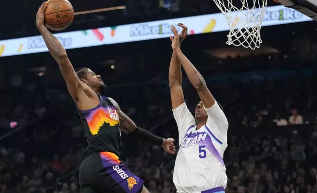 Phoenix Suns guard Jalen Green, left, goes up for a dunk against Utah Jazz forward Cody Williams (5) during the first half of an NBA basketball game, Saturday, March 28, 2026, in Phoenix. (AP Photo/Ross D. Franklin)