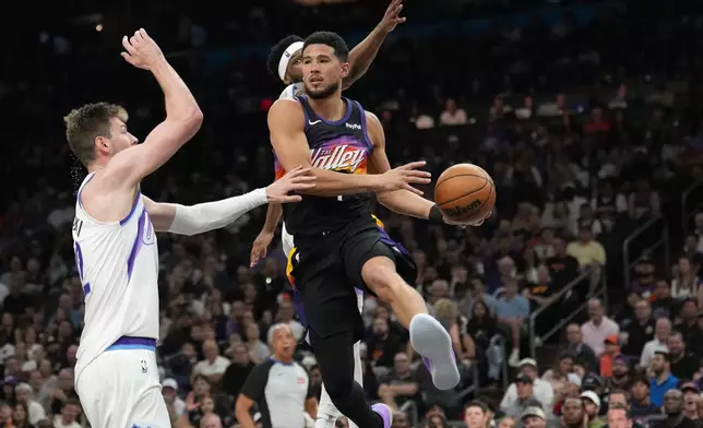 Phoenix Suns guard Devin Booker, right, looks to pass the ball against Utah Jazz forward Kyle Filipowski, left, during the first half of an NBA basketball game, Saturday, March 28, 2026, in Phoenix. (AP Photo/Ross D. Franklin)