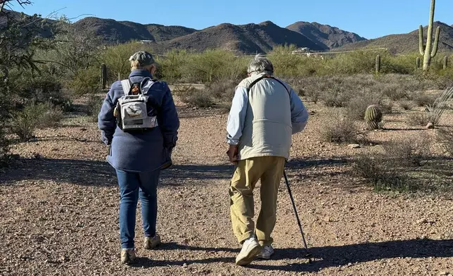 Group leader Marcia OBara, left, wearing an oxygen pack for her COPD, and birding enthusiast Rhea Guertin walk down a smooth dirt path during an accessible outing at Feliz Paseos Park in Tucson, Ariz., on Feb. 4, 2026. (Anita Snow via AP)