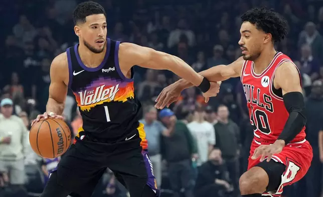 Phoenix Suns guard Devin Booker (1) shields the ball from Chicago Bulls guard Tre Jones during the first half of an NBA basketball game, Thursday, March 5, 2026, in Phoenix. (AP Photo/Rick Scuteri)