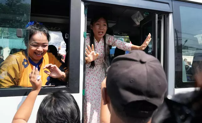Released prisoners, in a bus, are welcomed by family members and colleagues after they left Insein Prison Monday, March 2, 2026, in Yangon, Myanmar. (AP Photo/Thein Zaw)