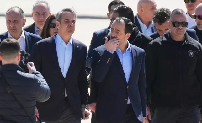 Greece's Prime Minister Kyriakos Mitsotakis, left, is welcomed by Cyprus President Nikos Christodoulides, second right, ahead of their meeting with French President Emmanuel Macron at Andreas Papandreou Air Base in Paphos, Cyprus, on Monday, March 9, 2026. (AP Photo/Petros Karadjias)