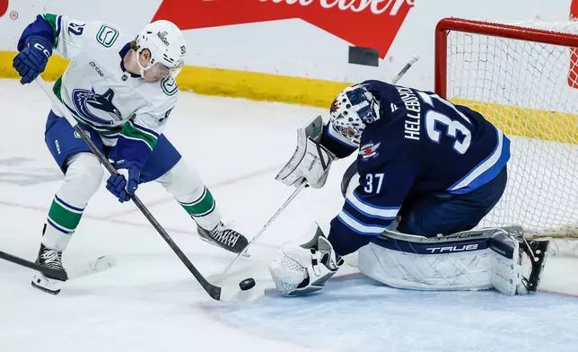 Winnipeg Jets goaltender Connor Hellebuyck (37) saves the shot from Vancouver Canucks' Liam Ohgren (92) during the first period of an NHL game in Winnipeg, Saturday, March 7, 2026. (John Woods/The Canadian Press via AP)