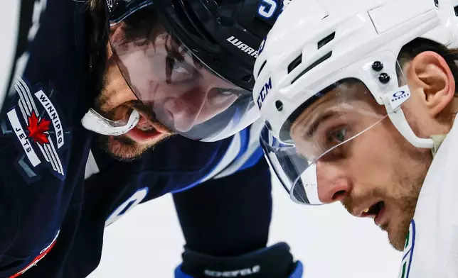 Winnipeg Jets' Mark Scheifele, left, and Vancouver Canucks' Teddy Blueger face-off during the second period of an NHL hockey game in Winnipeg, Manitoba, Saturday, March 7, 2026. (John Woods/The Canadian Press via AP)