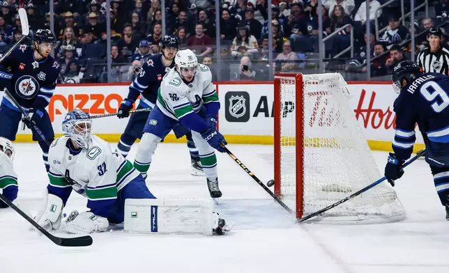 Vancouver Canucks' Victor Mancini (90) stops a shot by Winnipeg Jets' Alex Iafallo (9) during second period NHL action in Winnipeg, Saturday, March 7, 2026. (John Woods/The Canadian Press via AP)